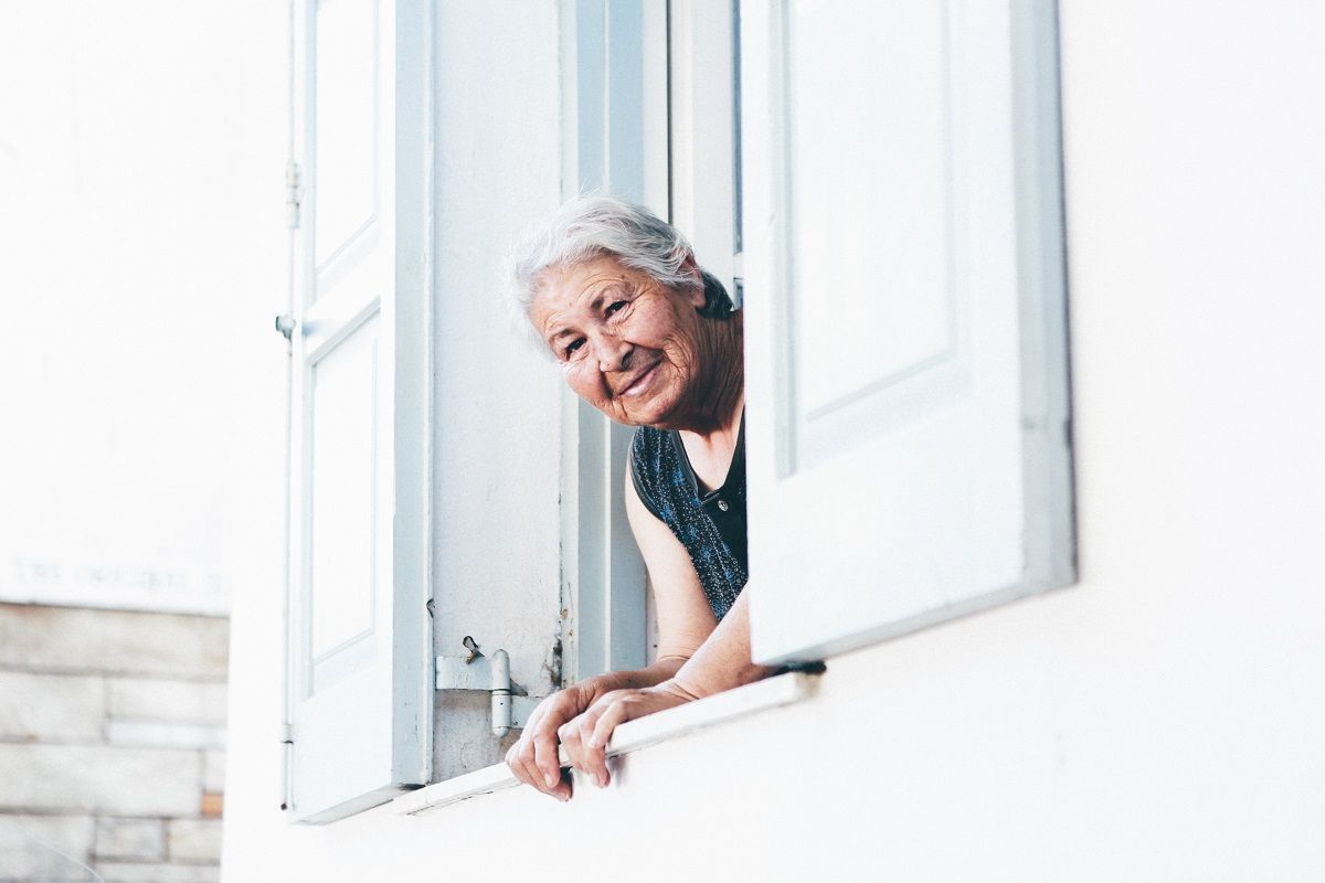 Idős nő néz ki az ablakon
