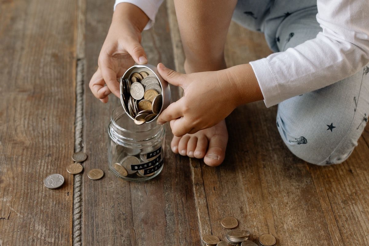 Pizsamás gyerek pénzt pakol egy üvegbe